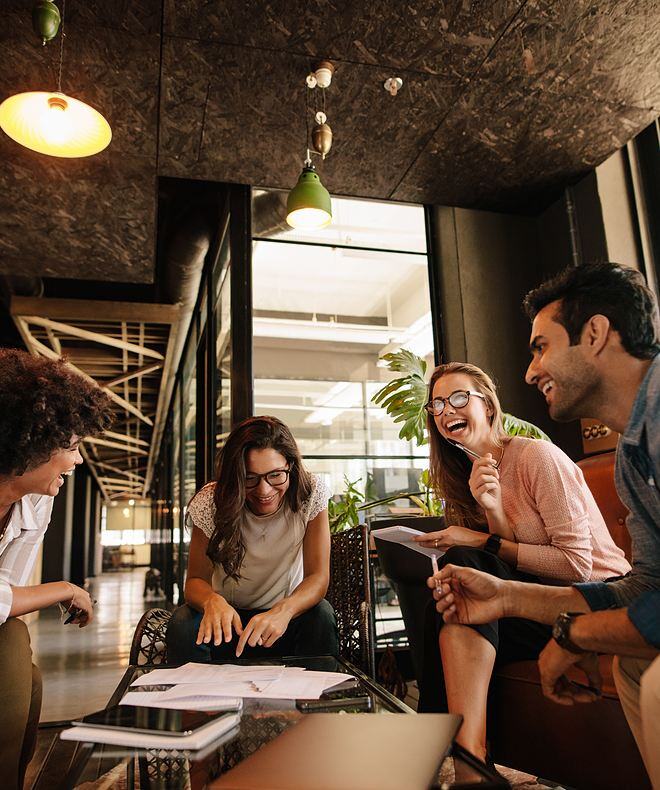 Four coworkers discussing a project, connecting and laughing together.
