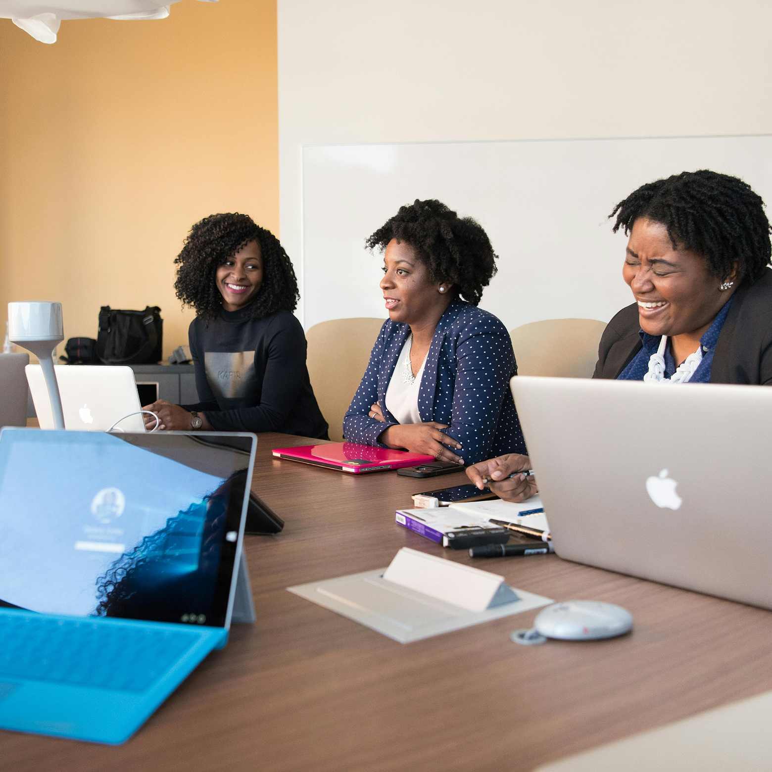 Image of a business team engaged in a meeting around a conference table, with a focus on collaboration and discussion. This image showcases how optimizing the meeting experience with Boom's advanced audio and video technology can increase productivity and efficiency. 