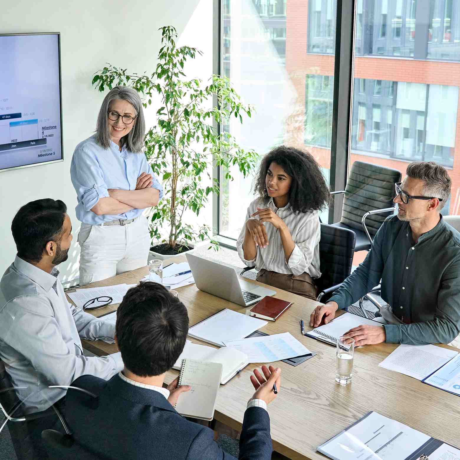 People in a conference room discussing data, utilizing Boom equipment to enhance communication and collaboration. Highlighting how Boom technology saves time and reduces costs by enabling efficient video conferencing and eliminating the need for travel. Facilitates productive meetings and effective data analysis.