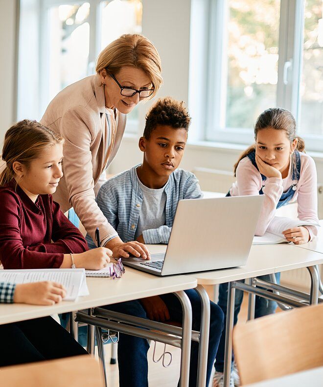 A group of elementary students having a computer class with their teacher in the classroom. With Boom technology, classroom learning experiences are enhanced, promoting interactive learning and seamless communication.