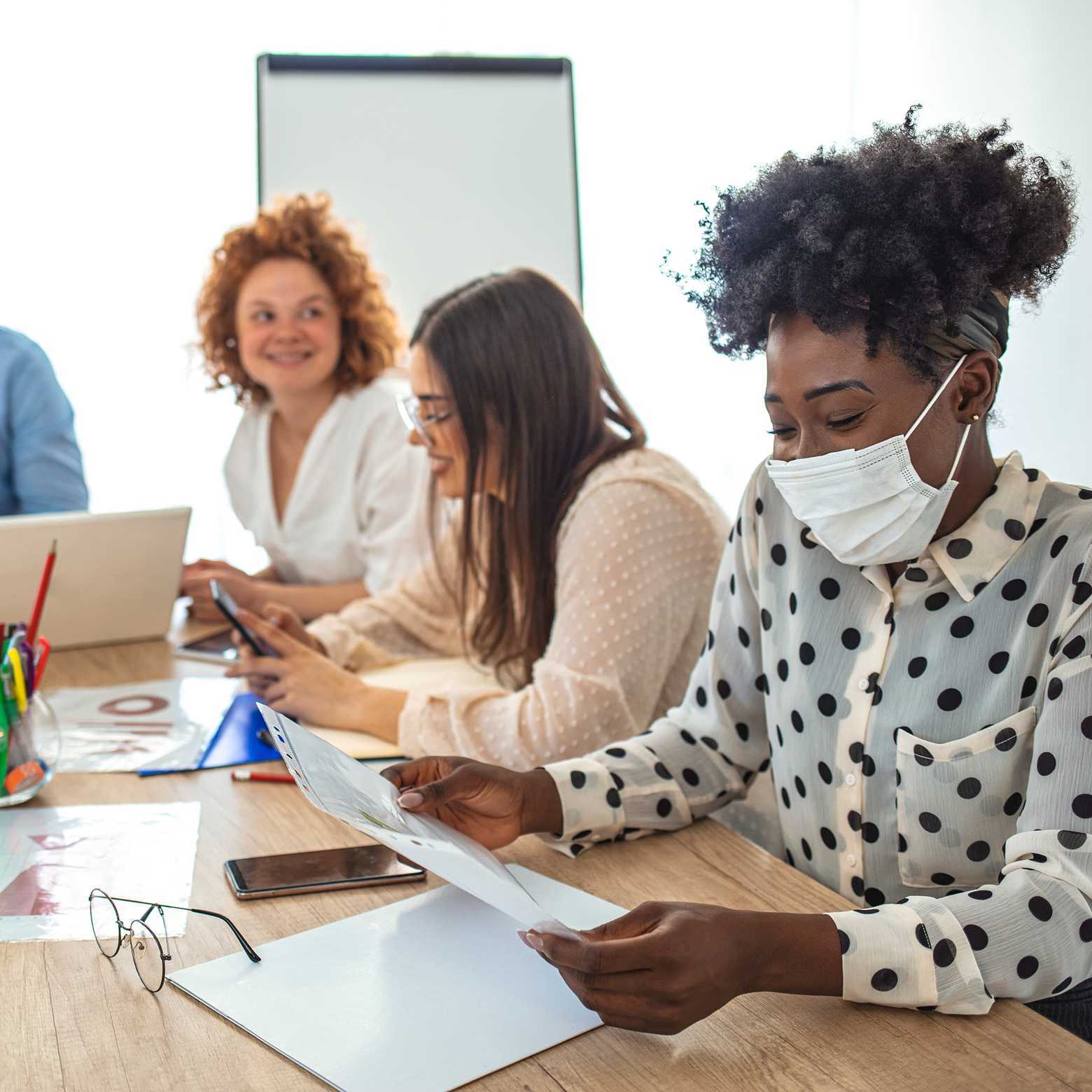 An employee works in a business office while wearing a medical face mask. With Boom Collaboration Equipment, meetings are transformed.