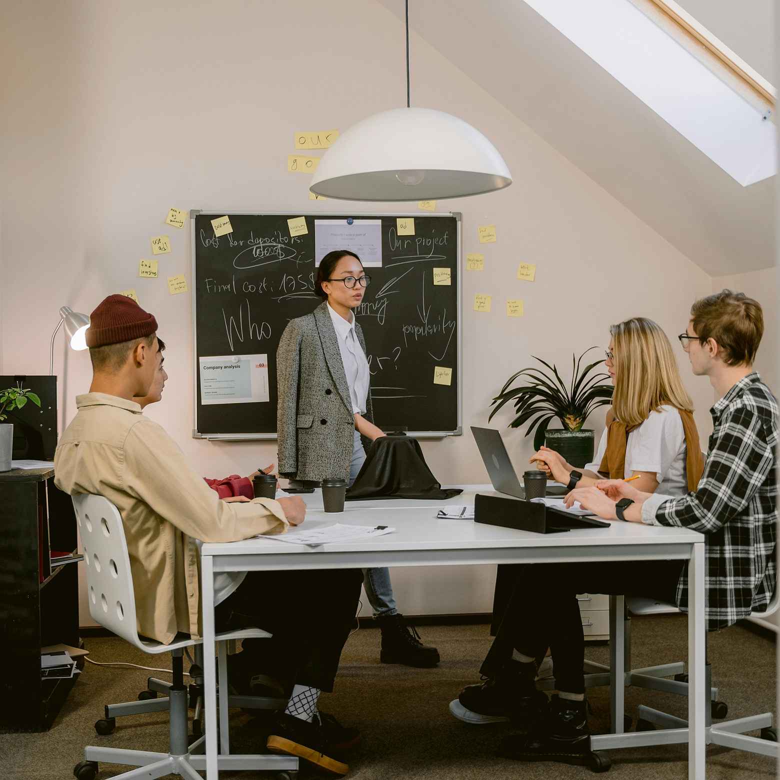 The image showcases four young professionals during a training session in a professional meeting room.
