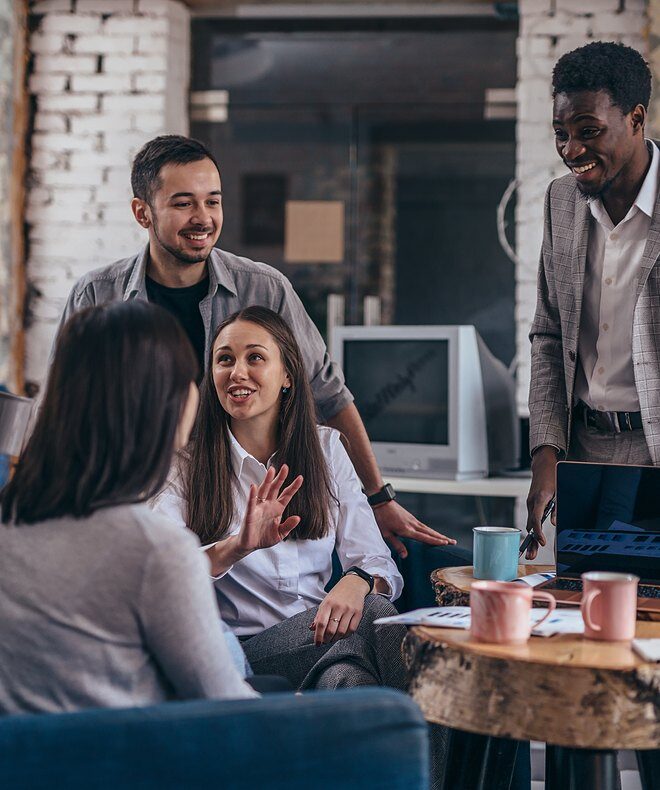 Small group of employees engage in a casual discussion, showcasing a collaborative and relaxed atmosphere. 