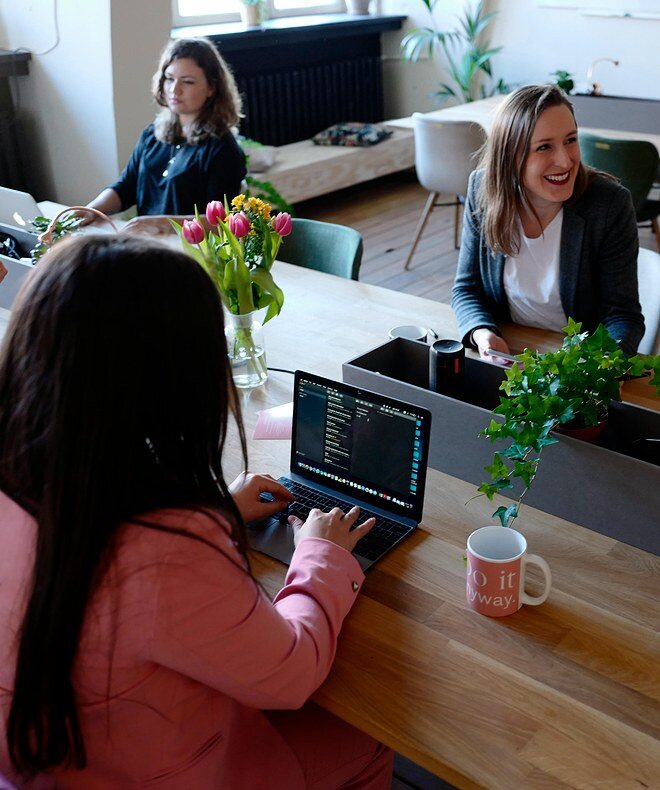 A young business woman laughing with her coworkers and demonstrating efficient communication in a business setting. Equipped with Boom Collaboration Equipment, the setup enhances productivity by video-enabling conference rooms. With high-quality cameras and speakerphones, Boom ensures seamless communication and collaboration across teams, optimizing meeting experiences and increasing overall efficiency.