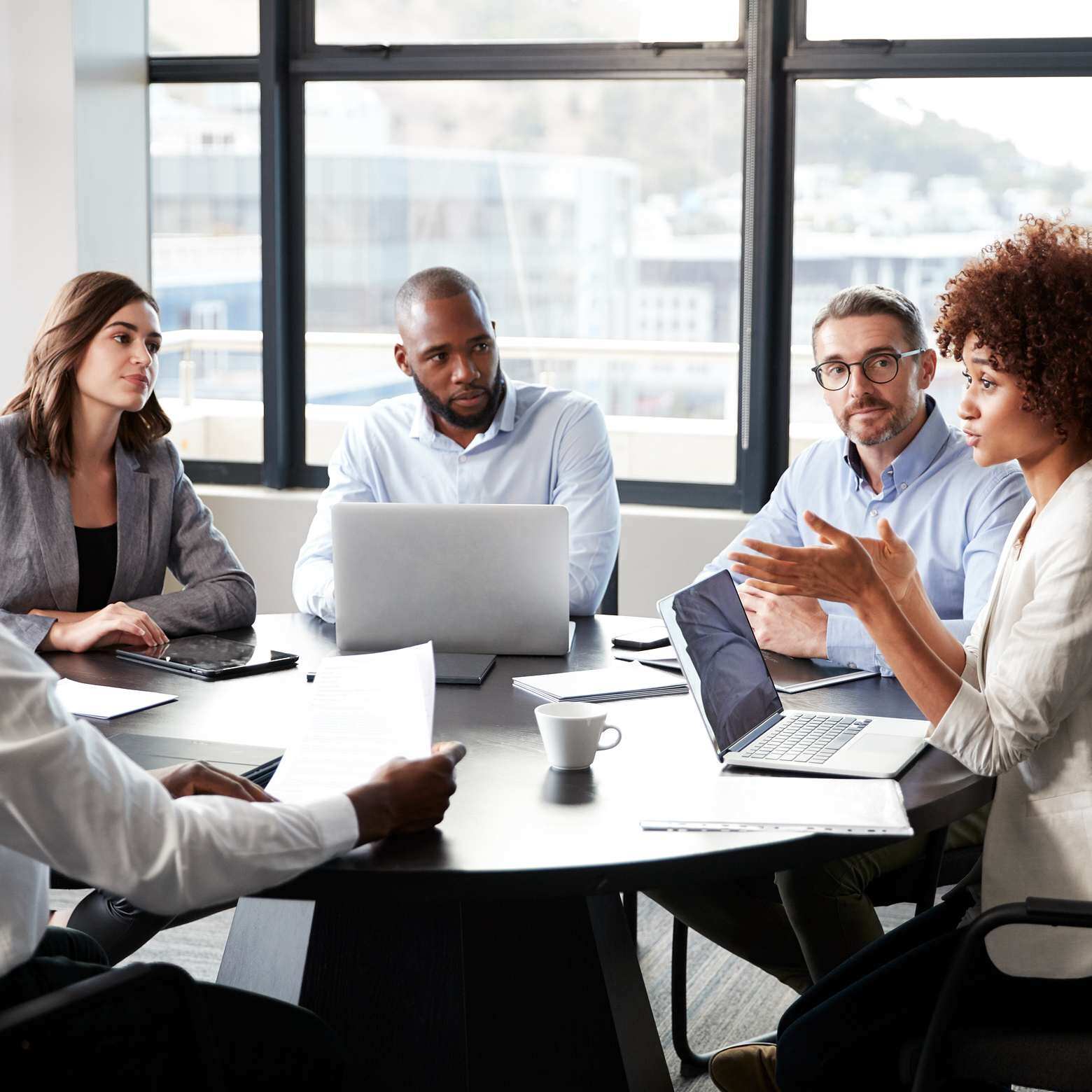 A professional businesswoman addressing colleagues at a corporate business meeting, utilizing Boom equipment for effective communication. 